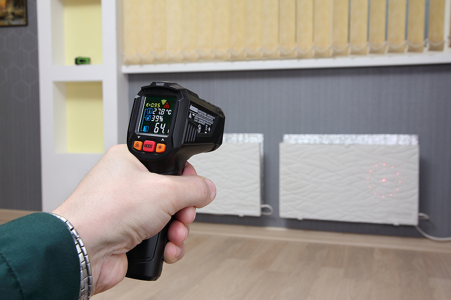 infrared thermometer in hand measures the temperature of heating radiators in a room