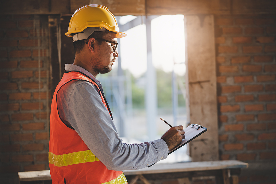 inspector checking structure of new property and taking note in the clipboard for review and fix the house before sell to client