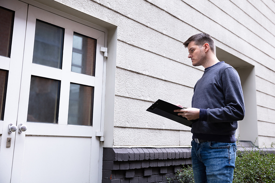 service man holding clipboard in hand standing in front of closed door