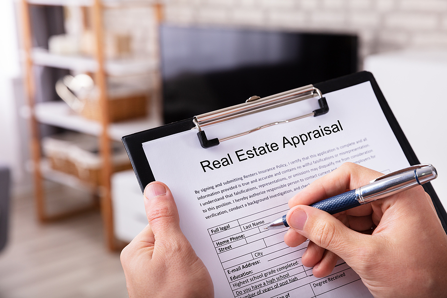 a man's hand filling real estate appraisal form at home